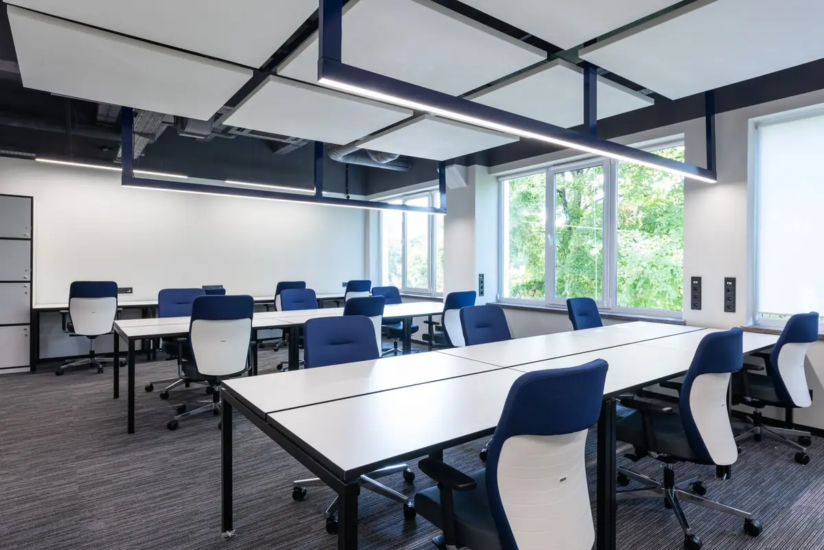 Bright, modern open-plan office with desks and blue chairs